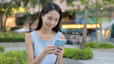 Şehirde akıllı telefon kullanan genç bir kadın.