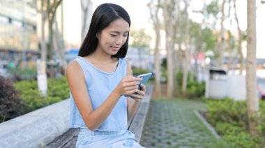 Parkta cep telefonu kullanan bir kadın.