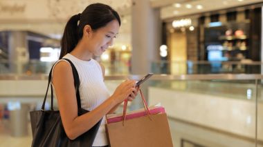 Smartphone kullanarak ve çanta tutan kadın 