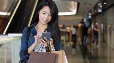 Cep telefonu kullanarak ve alışveriş torbaları tutan kadın