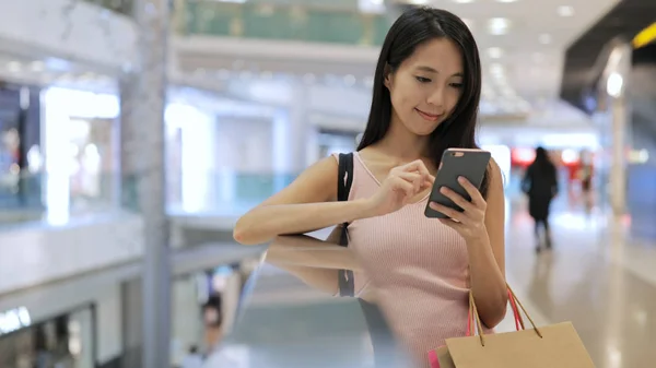 Mujer trabajando en el teléfono celular y sosteniendo bolsas de compras —  Fotos de Stock