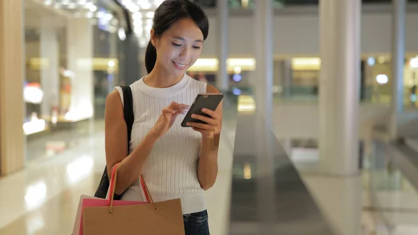 Frau geht einkaufen und benutzt Handy — Stockfoto