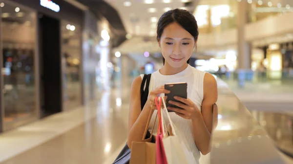 Frau benutzt Smartphone mit Einkaufstasche — Stockfoto