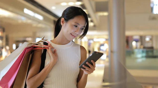 Vrouw bedrijf tassen en mobiel — Stockfoto