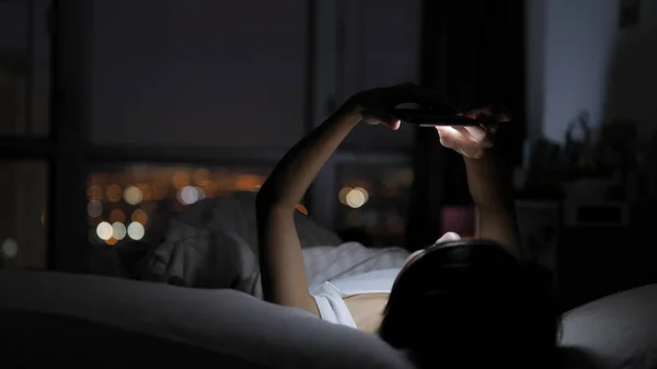 Mulher assistindo no celular e deitada na cama — Fotografia de Stock