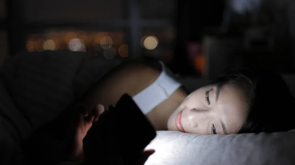 Wanita melihat smartphone dan berbaring di tempat tidur — Stok Foto