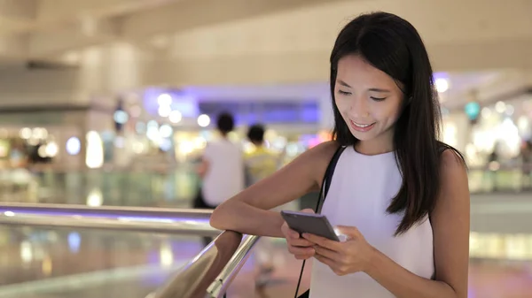 Vrouw met behulp van mobiele telefoon in winkelcentrum — Stockfoto