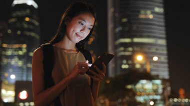 Şehirde akıllı telefon kullanan genç bir kadın. 