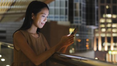 Gece şehirde akıllı telefon kullanan bir kadın.