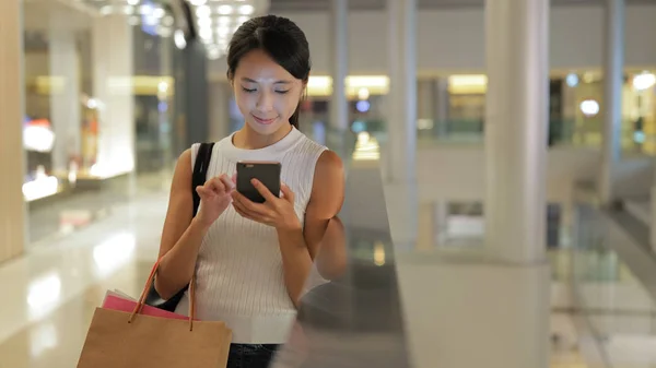 Mujer sosteniendo bolsas de compras y utilizando el teléfono celular —  Fotos de Stock