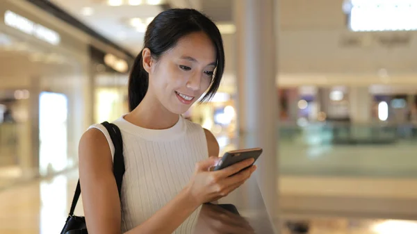 Frau benutzt Smartphone in Einkaufszentrum — Stockfoto