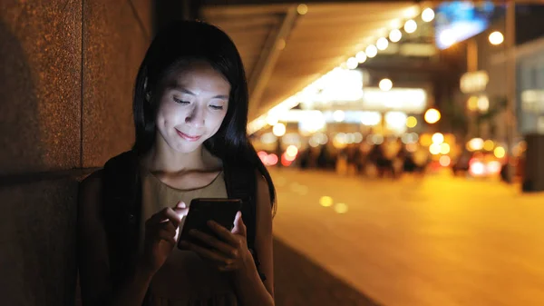 Mulher olhando para o celular na cidade à noite — Fotografia de Stock