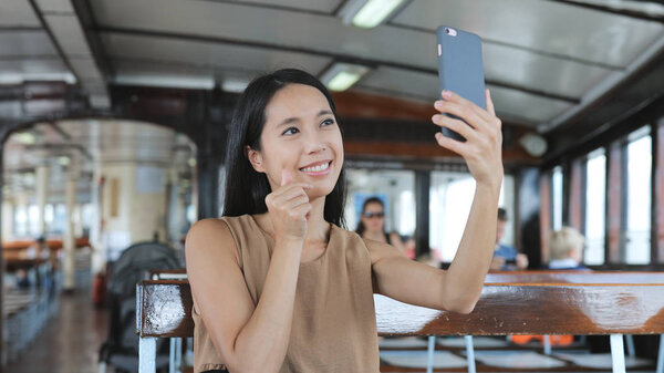 Woman taking selfie with cellphone on ferry