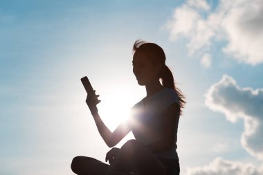 Günbatımı altında cep telefonu kullanan kadın