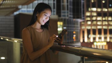 Gece şehirde akıllı telefon kullanan bir kadın.