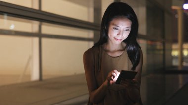 Geceleri cep telefonu kullanan bir kadın.