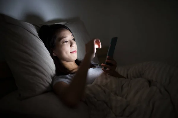 Mulher usando celular na cama à noite — Fotografia de Stock