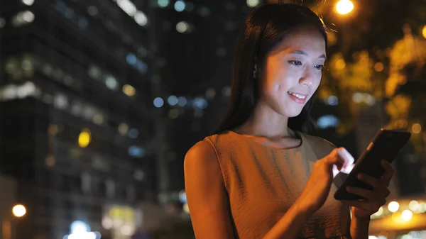 Vrouw met behulp van mobiele telefoon in de stad bij nacht — Stockfoto