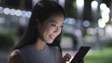 Geceleri cep telefonu kullanan bir kadın.