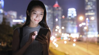 Geceleri cep telefonu kullanan bir kadın. 