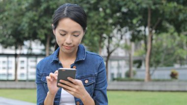 Parkta cep telefonu kullanan bir kadın.