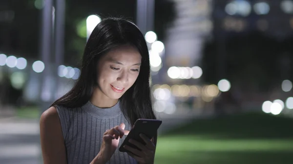 Kvinna som använder smartphone i staden på natten — Stockfoto