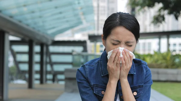 Woman sneeze in the city — Stock Photo, Image