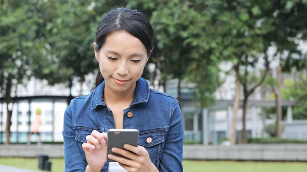 Parkta cep telefonu kullanan kadın