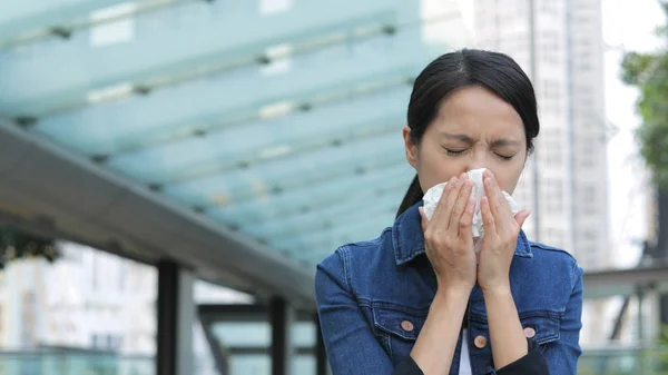 Mujer estornuda en la ciudad — Foto de Stock