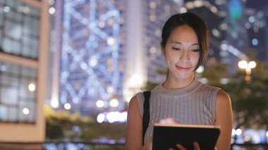 Şehirde tablet bilgisayar kullanan bir kadın. 