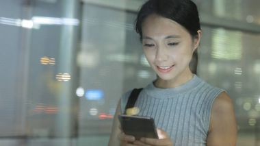 Geceleri cep telefonu kullanan bir kadın.