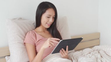 yatağın üzerine tablet bilgisayar kullanan kadın 