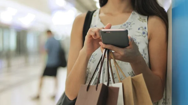 Женщина держит мобильный телефон и сумки для покупок — стоковое фото