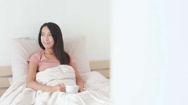 Mujer sosteniendo una taza de té en la cama — Foto de Stock