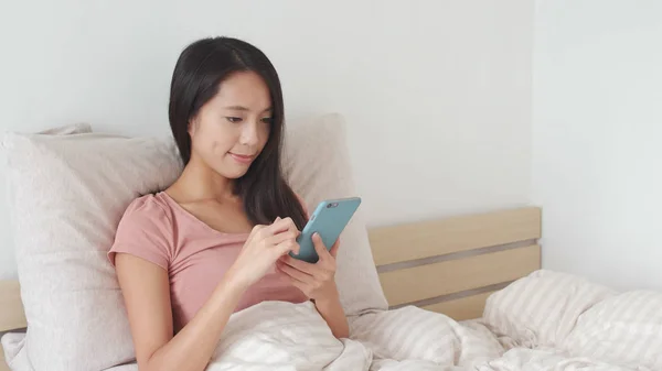 stock image Woman using mobile phone on bed 