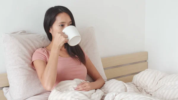 Frau trinkt Wasser auf dem Bett — Stockfoto