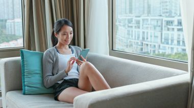 Evde cep telefonu kullanan bir kadın 