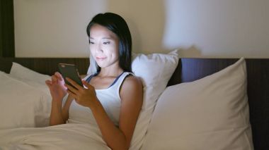 Yatakta cep telefonu kullanan kadın. 