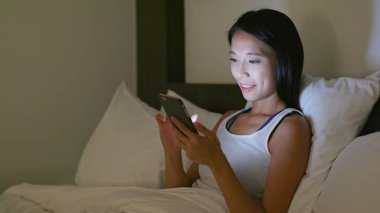 Yatakta cep telefonu kullanan kadın. 