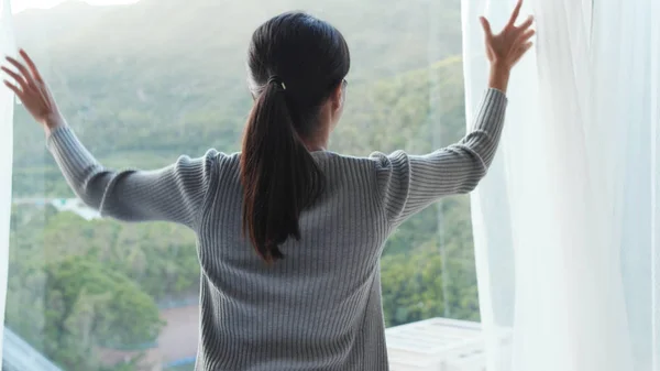 Vrouw onthullen het venster gordijn thuis — Stockfoto