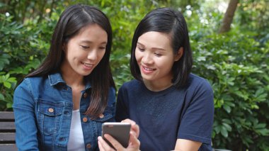 Cep telefonu ile parkta konuşan arkadaşlar 