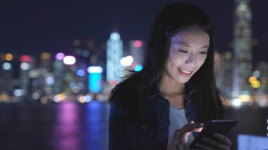 Geceleri cep telefonu kullanan bir kadın. 