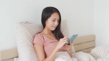 Yatakta cep telefonu kullanan kadın. 