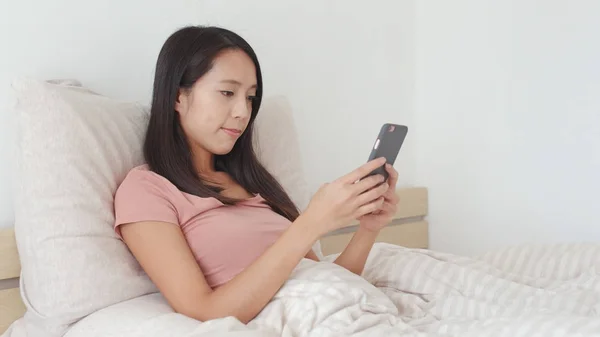 Mulher usando telefone celular na cama — Fotografia de Stock