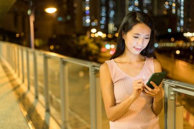 Asyalı kadın cep telefonunuzun gece izlerken 