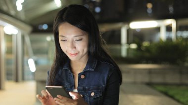 Geceleri cep telefonu kullanan bir kadın. 