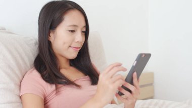 Yatakta cep telefonu kullanan kadın. 