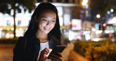 Geceleri cep telefonu kullanan bir kadın. 