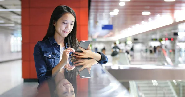 Vrouw met behulp van mobiele telefoon in station — Stockfoto