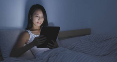 yatağın üzerine tablet bilgisayar kullanan kadın 